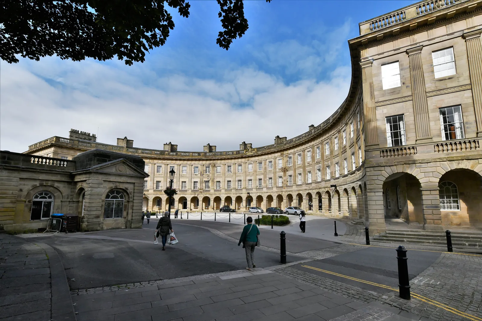 The curved stone facade of the Crescent in Buxton under a blue sky